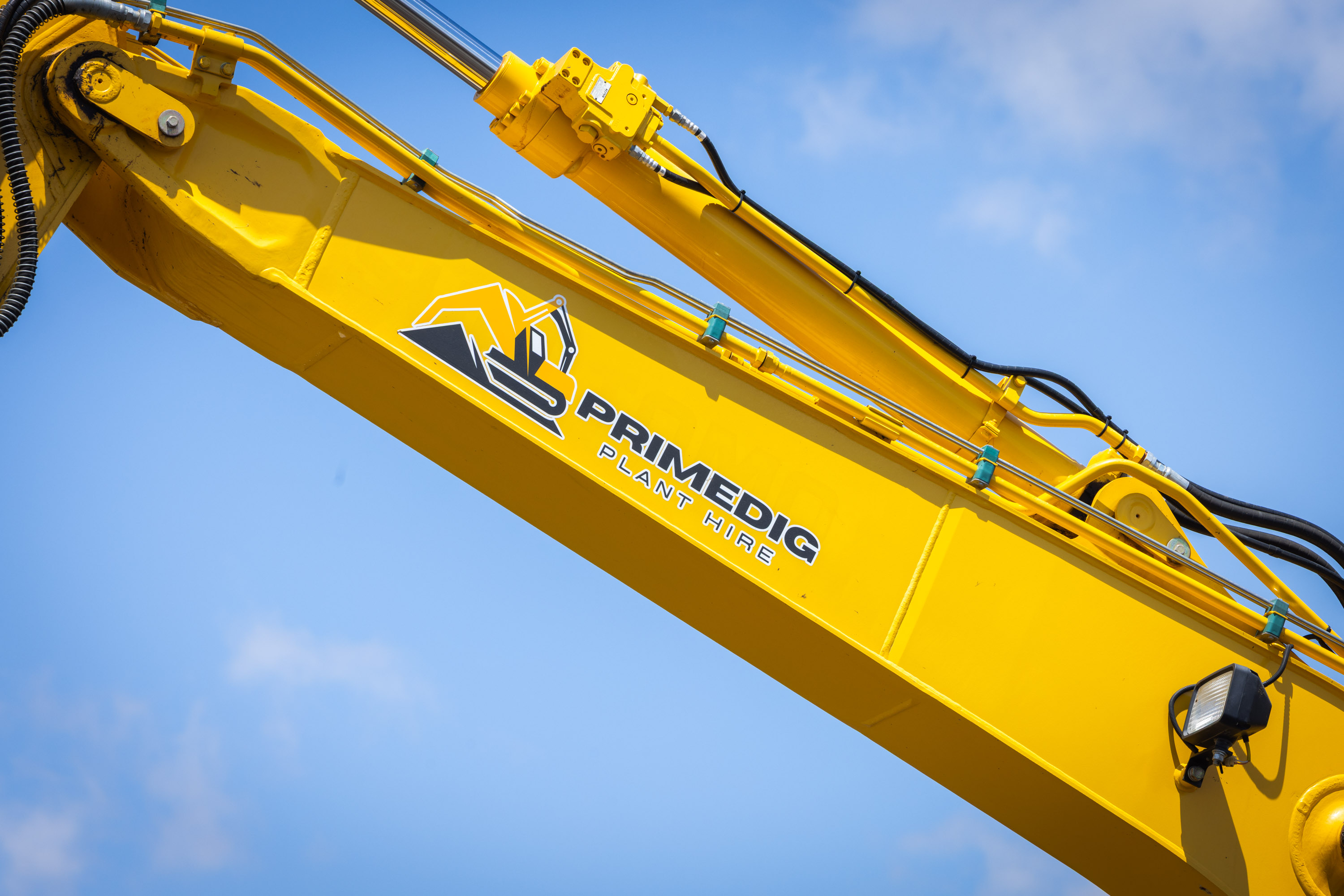 Sumitomo excavator boom in PrimeDig livery against a clear sky